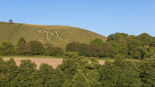 View of Cerne Abbas chalk giant beyond the trees in autumn in Dorset